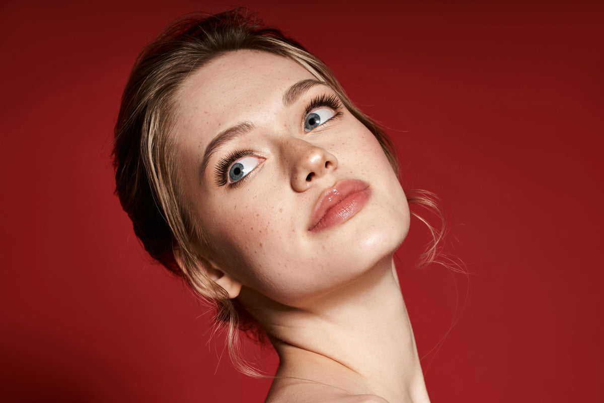 The Usual Lash beauty portrait with defined lashes against a red background